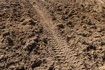 traces of a tractor on the soil of a field during tillage, soil in a field with traces of passing heavy agricultural machinery after tillage