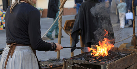 mujer herrera forjadora en el yunque trabajando con el martillo manos forja fuego 4M0A8448-as25