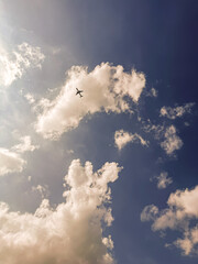 Błękitne niebo, białe chmury kłębiaste, lecący samolot - koncept podróżowania. Wakacje, urlop, podróż służbowa. © malgo_walko