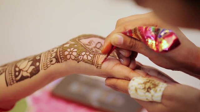 Mehndi being applied on a woman&rsquo;s hand as part of puja preparation for Indian festivals