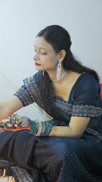 Indian woman in blue saree holding a decorated thali during a festive ceremony