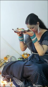 Indian woman in blue saree holding a decorated thali during a festive ceremony
