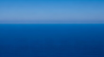 Obraz premium A serene view of the deep blue sea meeting the lighter blue sky on the horizon, creating a calming and peaceful seascape