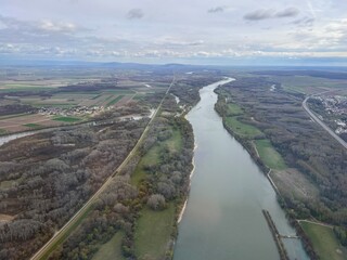 Aerial view of the Danube River near Vienna Airport, with fields and wind turbines in the background.