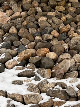 Background: colorful pebbles of various sizes, covered in the foreground by a light layer of snow