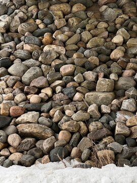 Background: colorful pebbles of various sizes, covered in the foreground by a light layer of snow