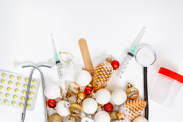 Top flat lay with a medical theme and merry Christmas and a happy new year. Syringes and pills mixed with Christmas toys. Isolated white background.