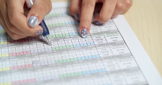 A focused individual meticulously updates data a detailed chart.