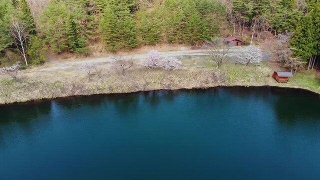 Aerial rise up above Yamagata lake coastline, countryside forested location in Japan in top of Mount Zaō