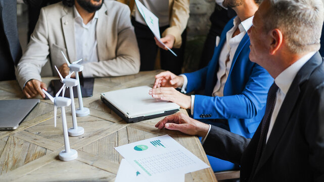 Business people working on sustainable innovation project - Green renewable energy and corporate concept - Focus on right senior man hand