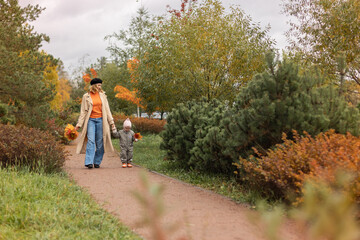 happy young mother and daughter  with autumn yellow leaves having fun time outside in the city park in autumn.