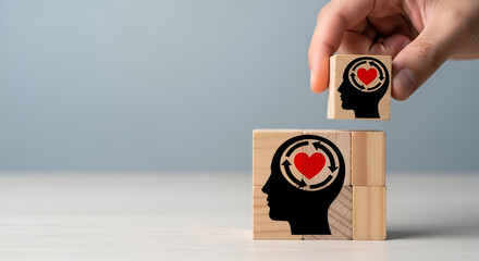Hand placing wooden block with head and heart icon