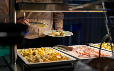 Hotel guests serve food on plates from the buffet in the hotel restaurant