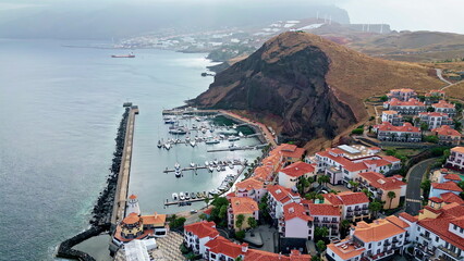 Ocean bay coastal settlement on mountain hills drone view. Houses on cliff