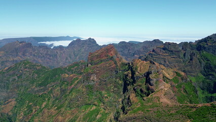 Aerial steep rocky mountains with green vegetation. Madeira landscape blue sky