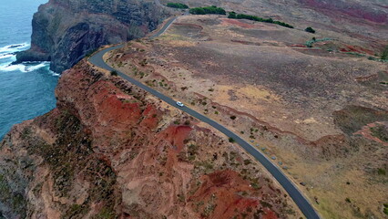 Drone view car riding picturesque coastal cliffs washed ocean. Vehicle moving