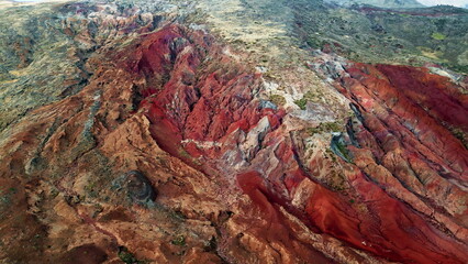 Drone steep rocky cliff with dominant red colors erosion marks. Rough stones