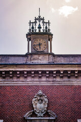 Milan, Italy, Europe: the clock and coat of arms on the roof of the facade of the internal courtyard of Bagatti Valsecchi Museum, historic house museum in Montenapoleone district
