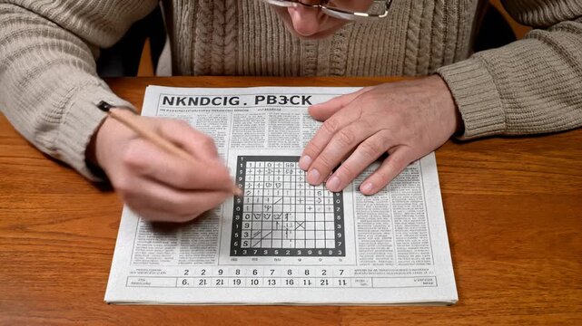 Man Solving a Crossword Puzzle in Newspaper With Pencil