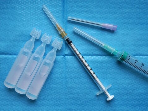 Ensemble de seringues, aiguilles et unidoses de s&eacute;rum physiologique sur fond de champ st&eacute;rile hospitalier