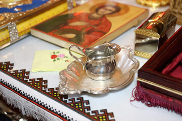 A metal jug of holy water on a table in a church.