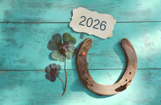 Horseshoe with lucky clover - 2026 greeting card horseshoe on wooden background - happy new year greetings, wishes
