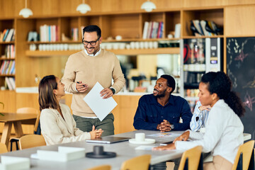 Fototapeta premium A man leads a Meeting With Colleagues In a Modern Office Café Setting During a Collaborative Brainstorm Over Documents And Coffee