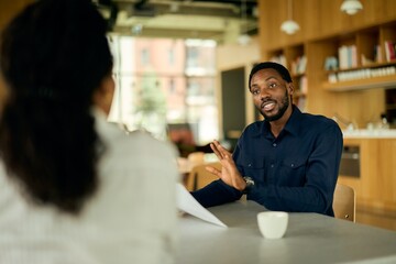 African-American Man In Deep Conversation With African-American Woman Over Documents In Café