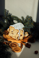 Christmas stollen on a wooden board with green branches of a Christmas tree. Christmas background, Christmas desserts