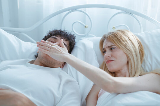 A young man is trying to stop his wife from snoring because she snores very loudly.