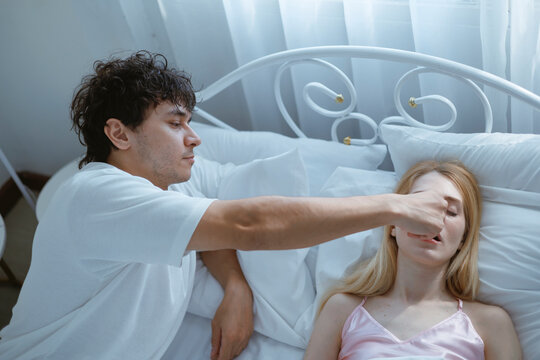 A young man is trying to stop his wife from snoring because she snores very loudly.