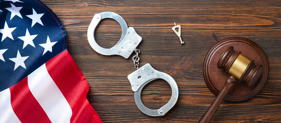 Judge gavel and handcuffs with American flag on a wooden desk. Symbolizes justice and law...