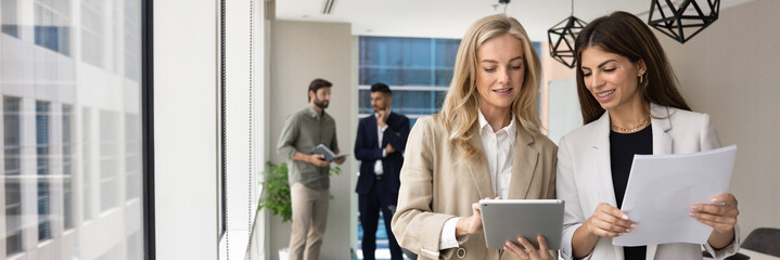 Two young female business colleagues consulting each other