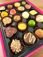 Closeup overhead shot of a colorful selection box of chocolates in a variety of bold shapes, patterns and textures.