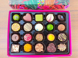 Closeup overhead shot of a colorful selection box of chocolates in a variety of bold shapes, patterns and textures.