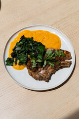 A plate of pork chop with silverbeet and sweet potato.