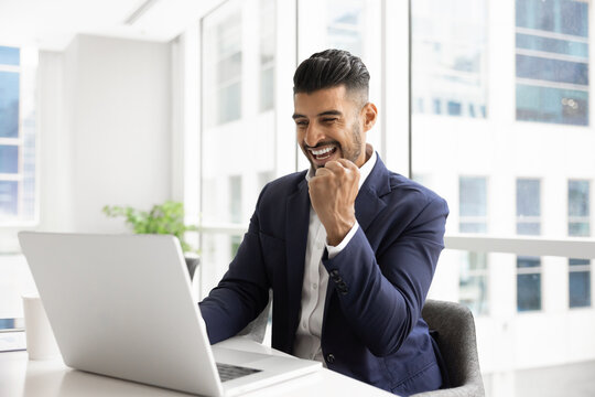Happy overjoyed Indian businessman man celebrating online triumph