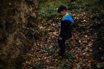 Boy walking alone in autumn forest feeling sad