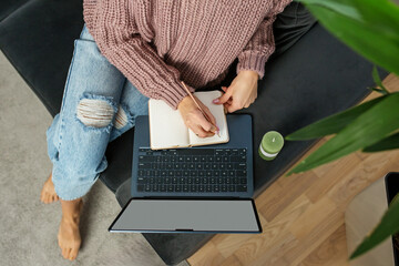 Woman writing in notebook while working from home
