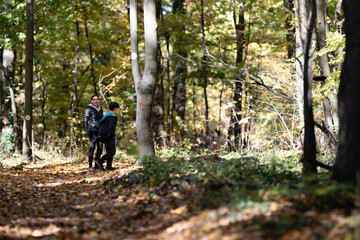 Obraz premium Mother and son enjoying autumn walk in forest