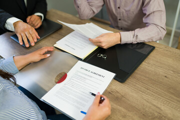 Closeup of couple signing divorce agreement with legal counsel