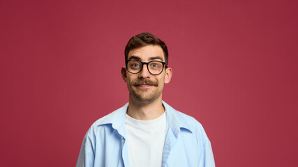 Cheerful man smiling slightly with pleased facial expression on red background. Concept of calm...