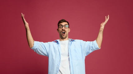 Excited man raising hands with joyful open mouth expressing surprise and happiness. Concept of...