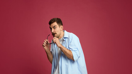 Curious man biting glasses with suspicious look showing hesitation and doubt. Concept of thinking...