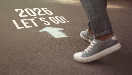New 2026 Year. Man walking toward arrow with numbers and phrase Let's Go! on asphalt, closeup