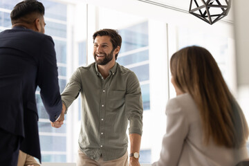 Positive motivated young professional man giving handshake to Indian employer
