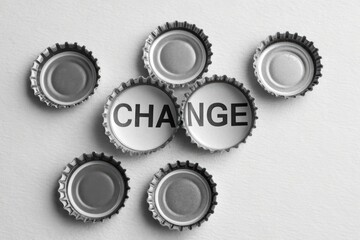 Bottle Caps Arranged to Spell Change on Light Background