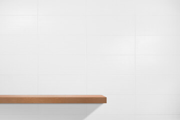 Blank wooden shelf hanging on the bathroom tile wall. © Supachai
