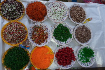 Assorted colorful Indian mukhwas mouth fresheners arranged in small bowls on stall table, top view