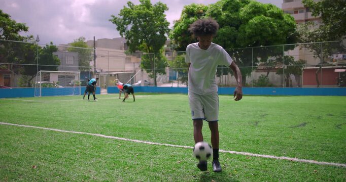 African American Latin man juggling soccer ball on urban field during friendly practice, demonstrating balance, coordination, and concentration, symbol of dedication to sport